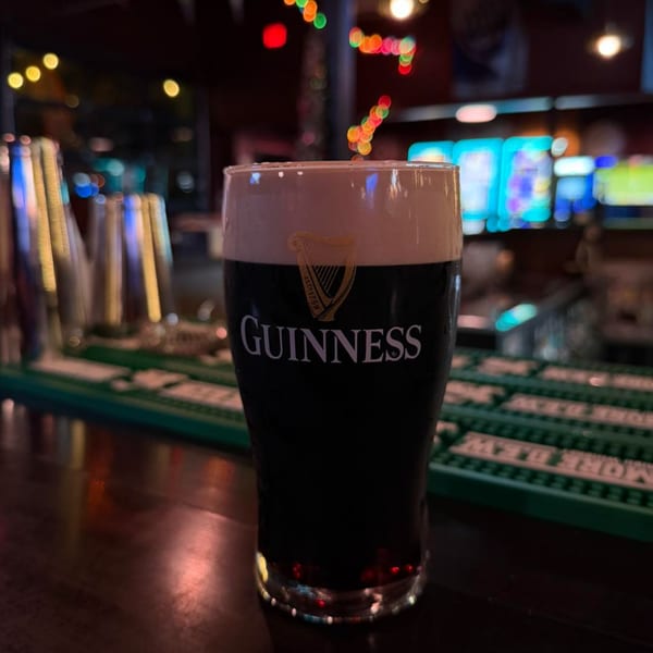A pint of Guinness beer with a creamy head sits on a dark bar at O'Larney's Pub.
