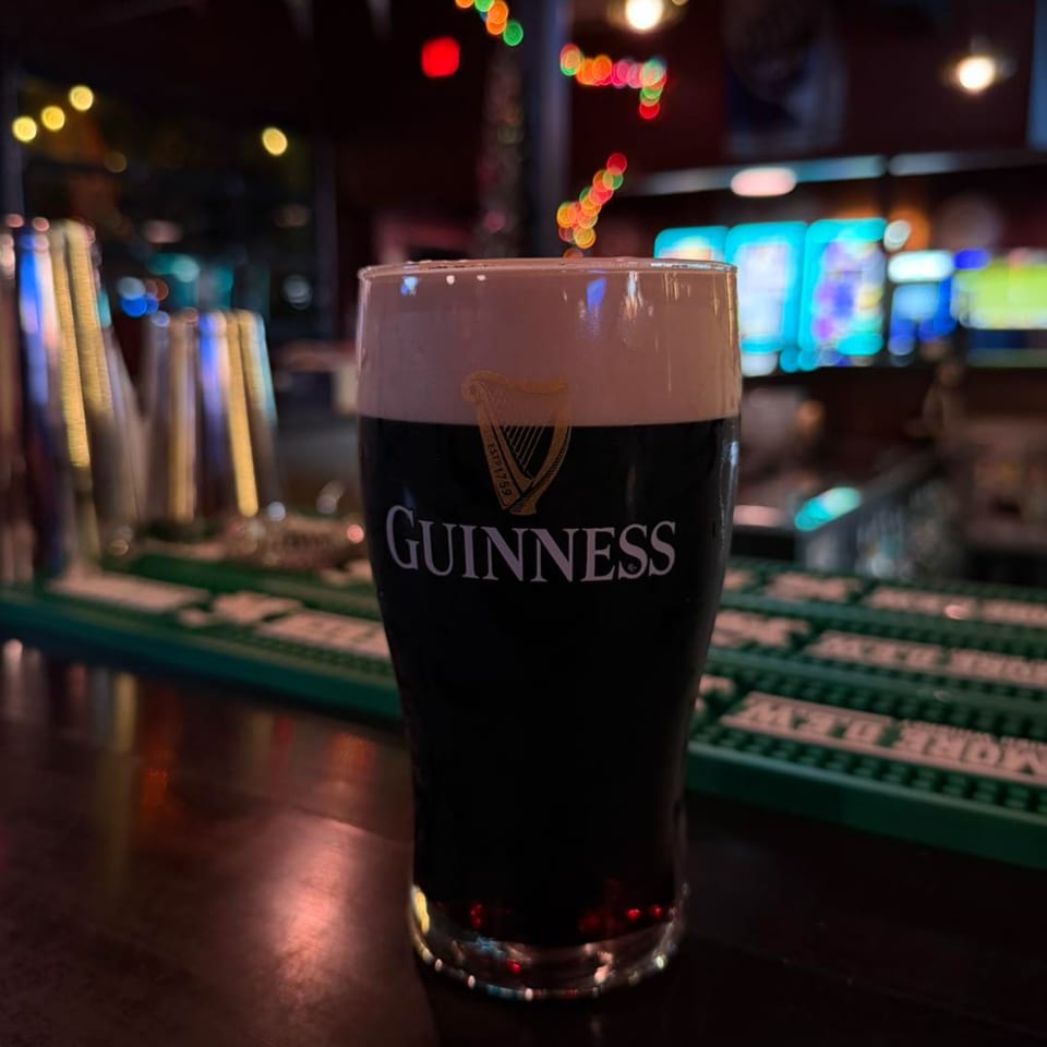 A pint of Guinness beer with a creamy head sits on a dark bar at O'Larney's Pub.
