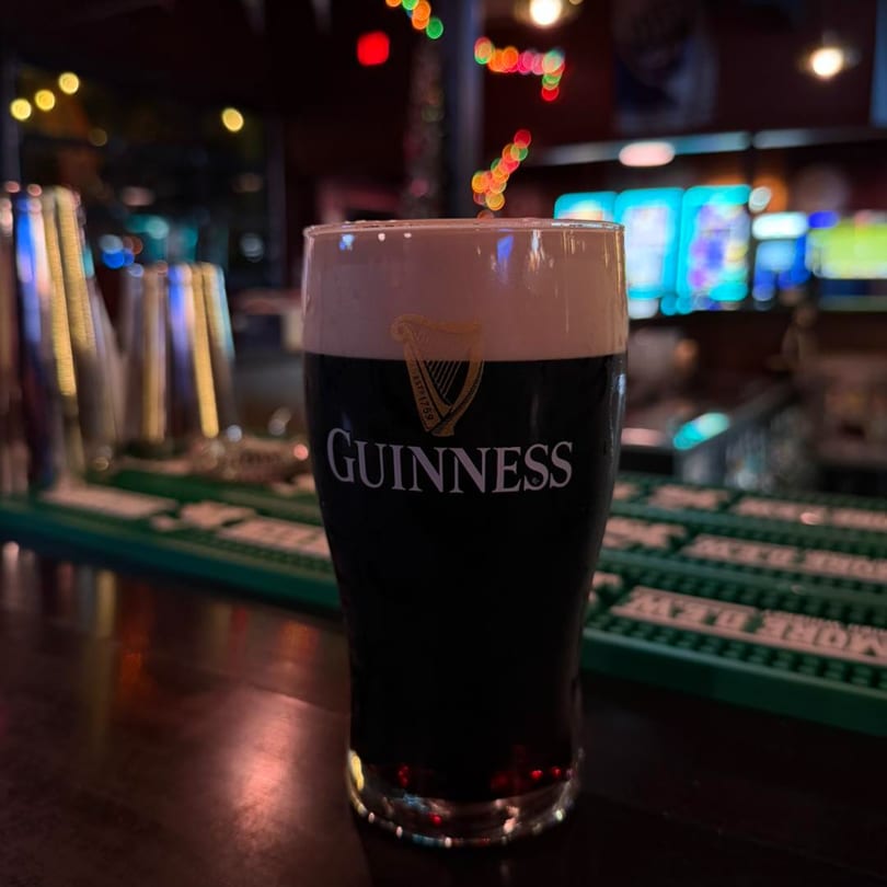 A pint of Guinness beer with a creamy head sits on a dark bar at O'Larney's Pub.
